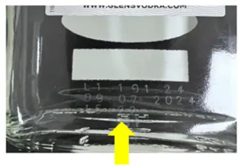 Food Standards Scotland A yellow arrow points to etched numbers on the back of a glass bottle