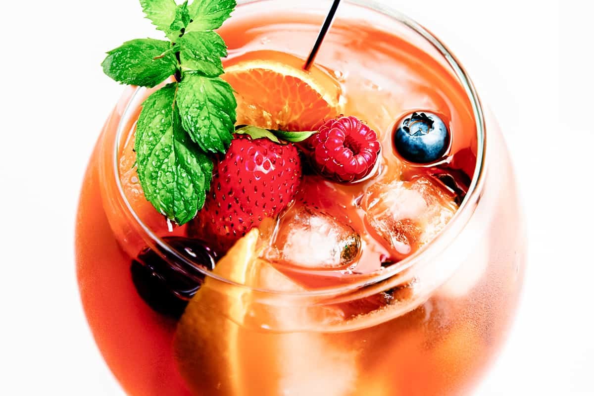 Refreshing rosé sangria with strawberries, raspberries, blueberries, orange slices, fresh mint, and ice.
