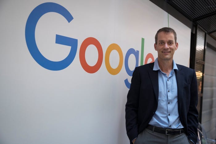 Jeff Dean, Google's Chief Scientist and employee number 30, in front of the Google logo before leaving to co-found Discovery Loop.