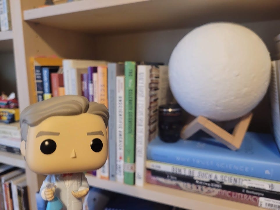 Funko Pop Bill Nye in front of a shelf of books