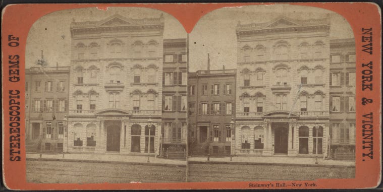 This black and white photograph shows an ornate four story building-Steinway Hall. There are arches over all of the windows and a grand entrance with columns on either side.