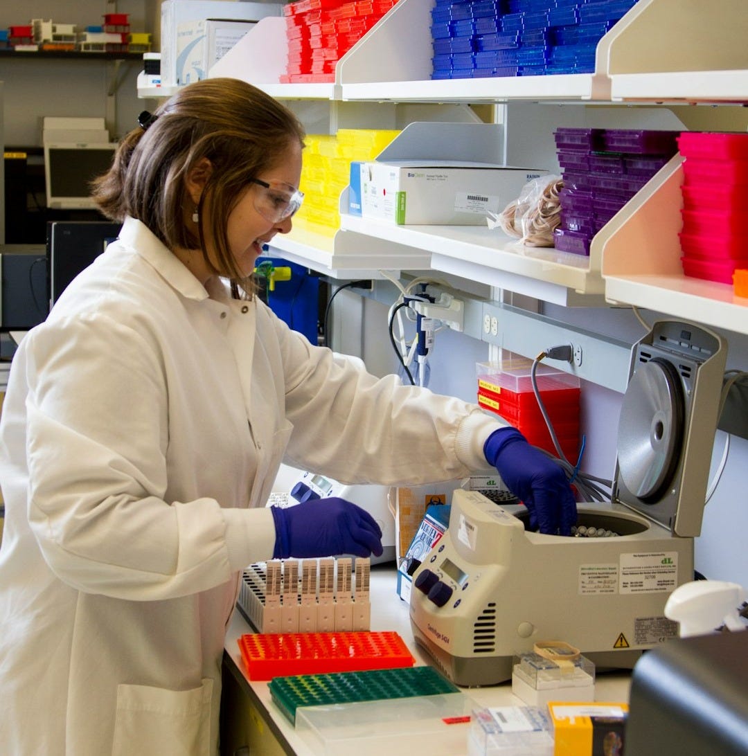 woman in white coat holding white and blue corded electronic device