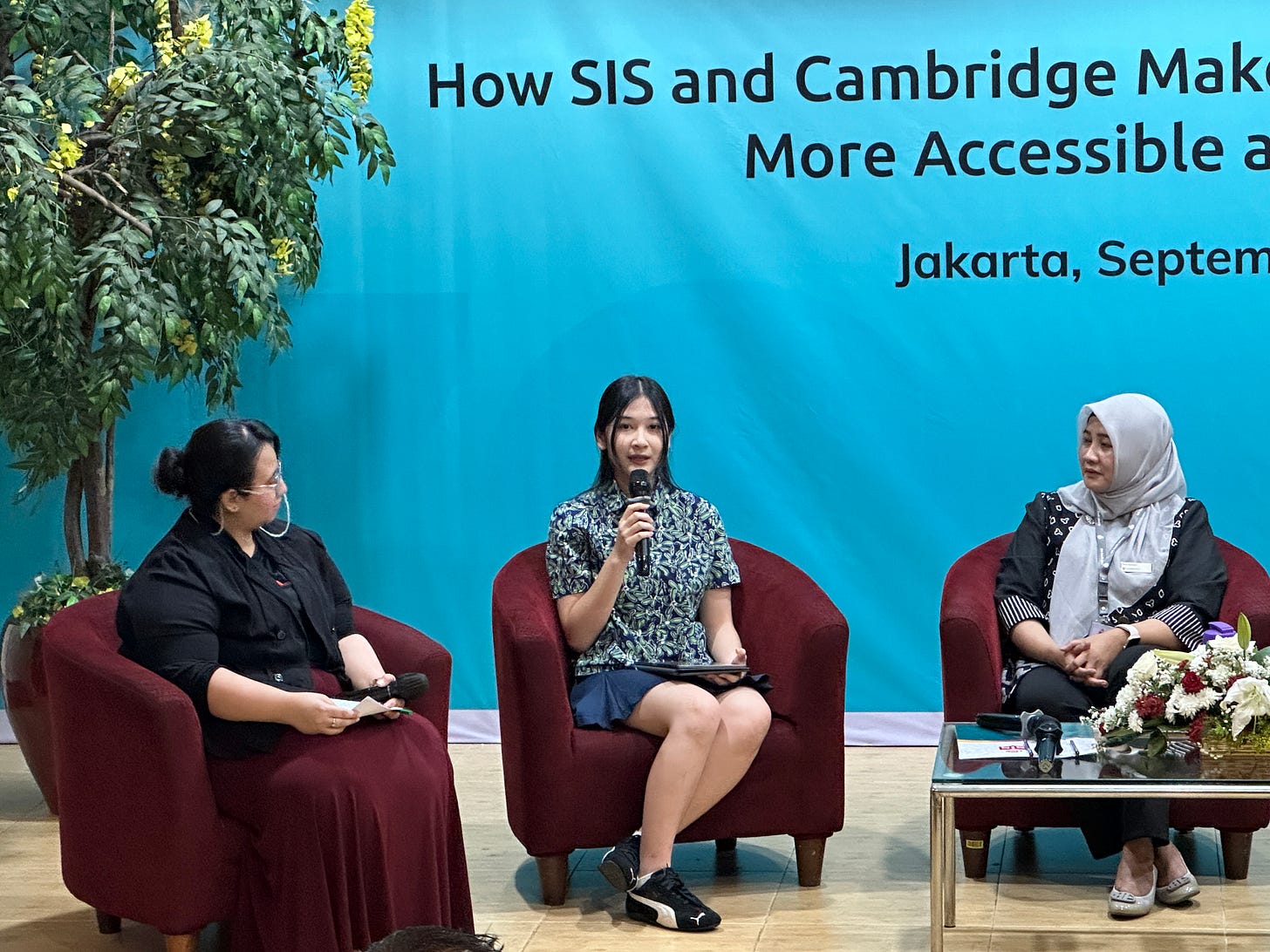 three women sit on the stage with the one on the center was seen speaking with a microphone three women sit on the stage with the one on the center was seen speaking with a microphone
