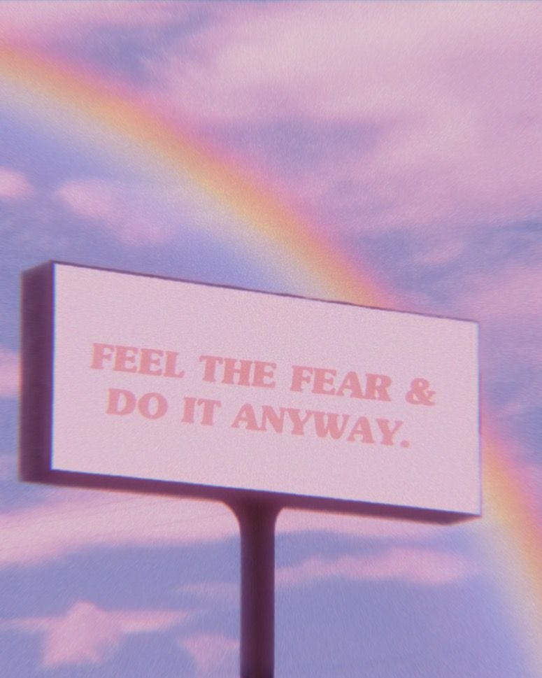 feel the fear and do it anyway billboard with a rainbow and pretty clouds in the background