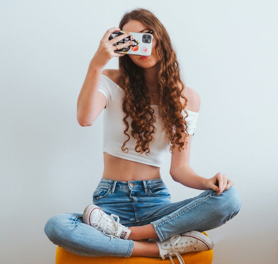 woman in pink long sleeve shirt and blue denim jeans sitting on white floor woman in pink long sleeve shirt and blue denim jeans sitting on white floor