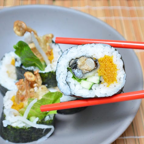 An assortment of futomaki sushi rolls, each filled with a variety of colorful ingredients like vegetables, pickled items, and vegan tamagoyaki. 