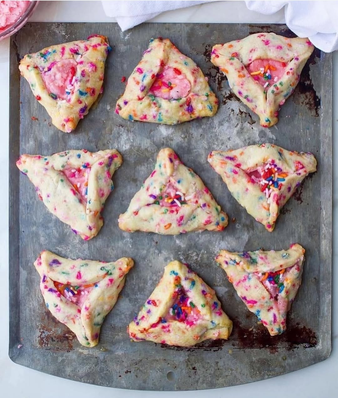 Amy’s Strawberry Champagne Rainbow Sprinkle Hamentaschen on a silver baking sheet