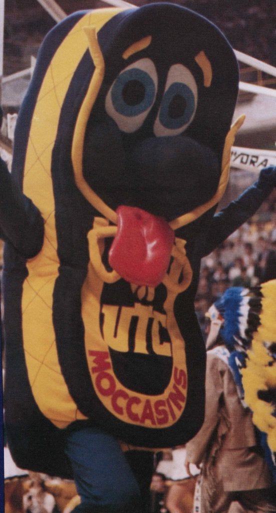 Color photograph of 1980s UTC mascot Mighty Moc, a blue and gold anthropomorphic shoe. Color photograph of 1980s UTC mascot Mighty Moc, a blue and gold anthropomorphic shoe.