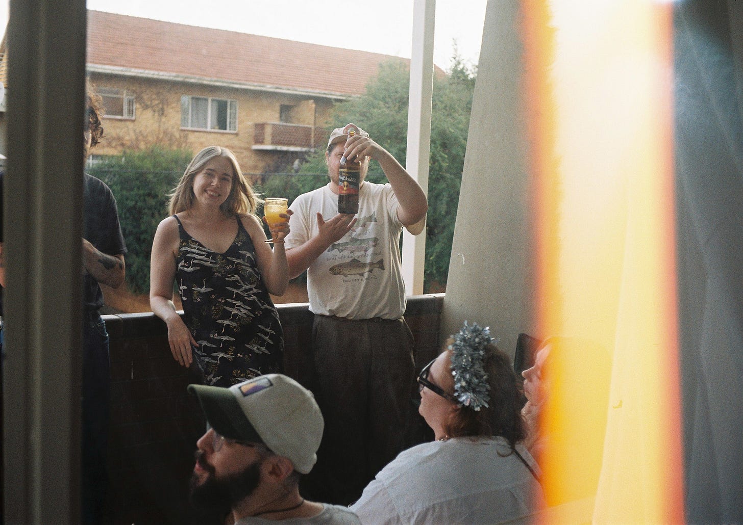 Film photo of friends drinking out of fancy glassware on a sunlit balcony | The Dance, a Substack by Simone-Claire Louw