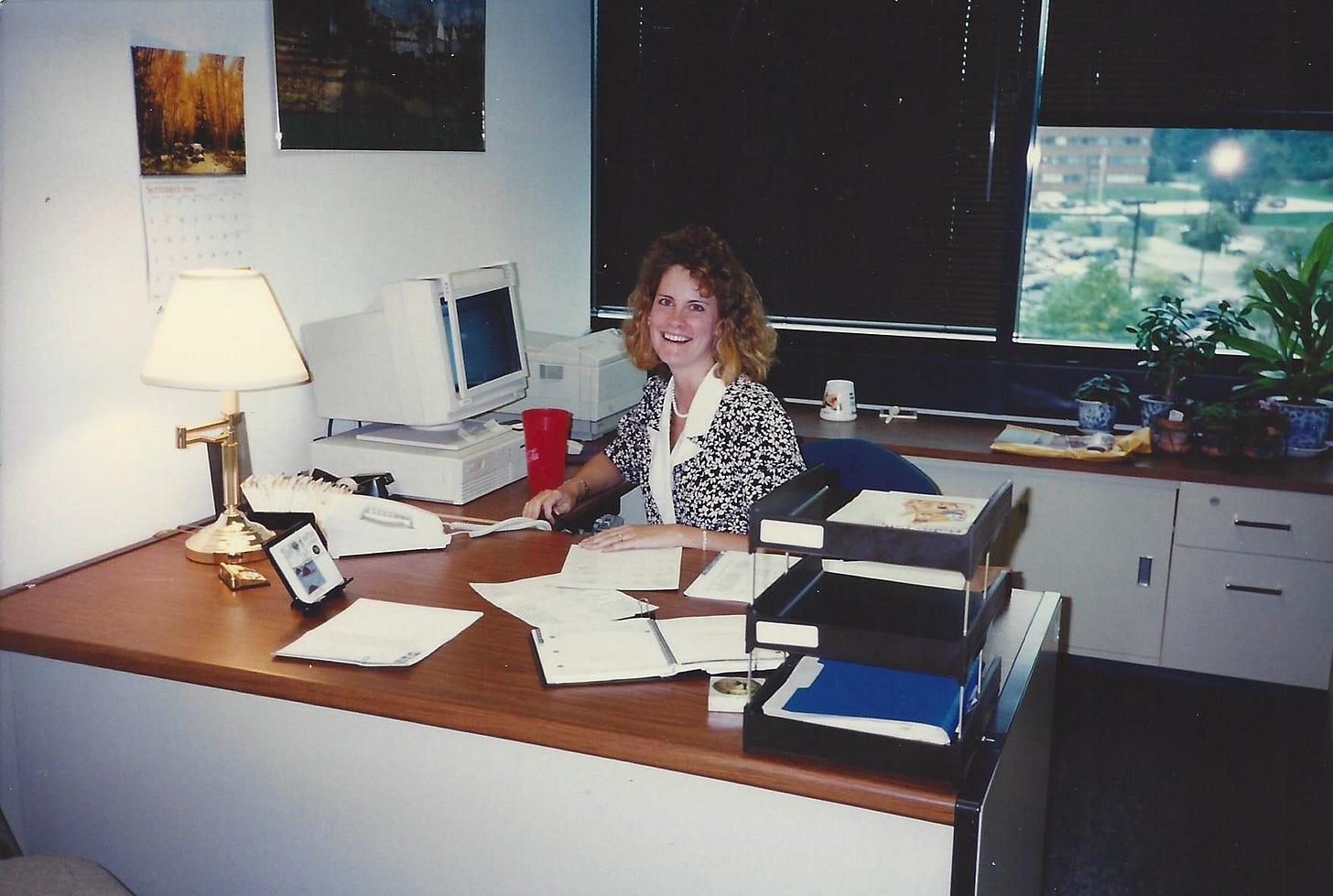 Scene from corporate America in the 1990s: Young woman sitting behind a desk Scene from corporate America in the 1990s: Young woman sitting behind a desk