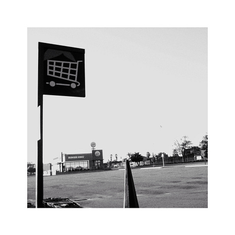 Three black and white images. A flag, a bus stop and a sign.