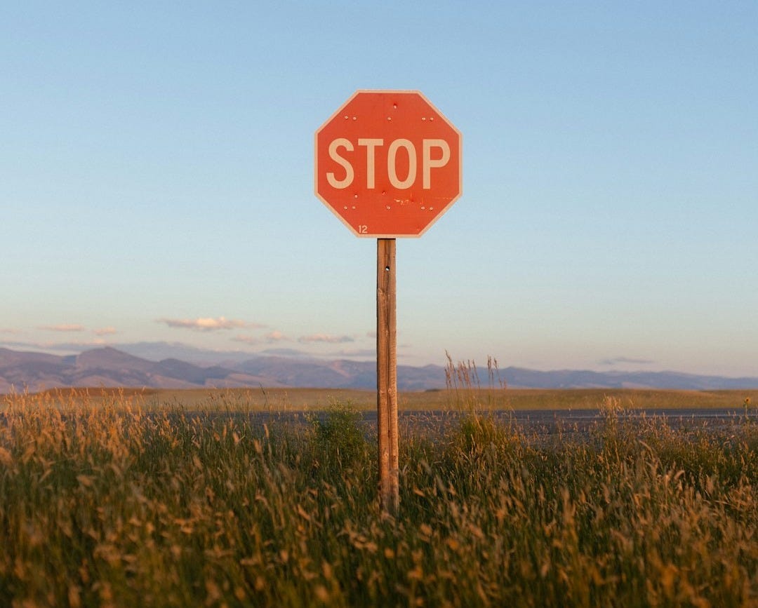 a red stop sign sitting on top of a lush green field a red stop sign sitting on top of a lush green field