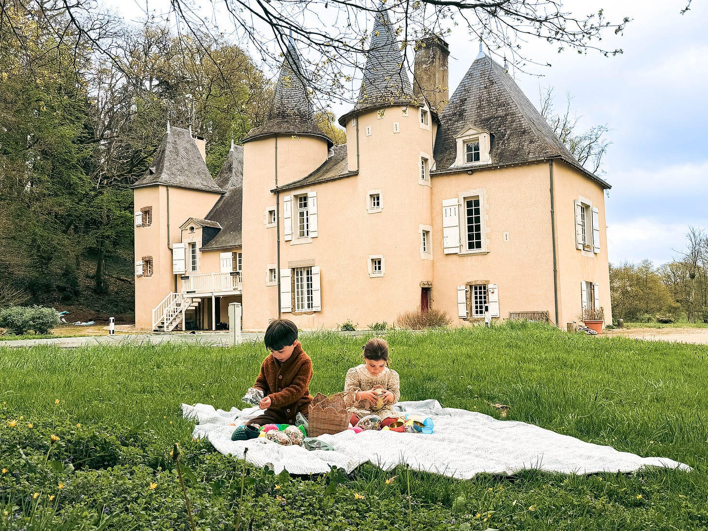 Two children sitting on a lawn in front of a French château opening Easter eggs Two children sitting on a lawn in front of a French château opening Easter eggs