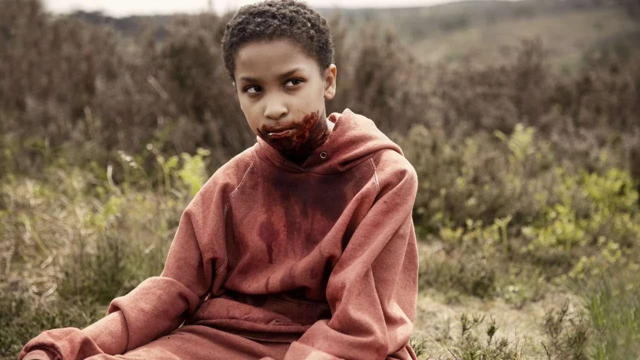 young Black girl with short hair and blood around her mouth sitting in a field, looking off to the side with an ambiguous expression young Black girl with short hair and blood around her mouth sitting in a field, looking off to the side with an ambiguous expression