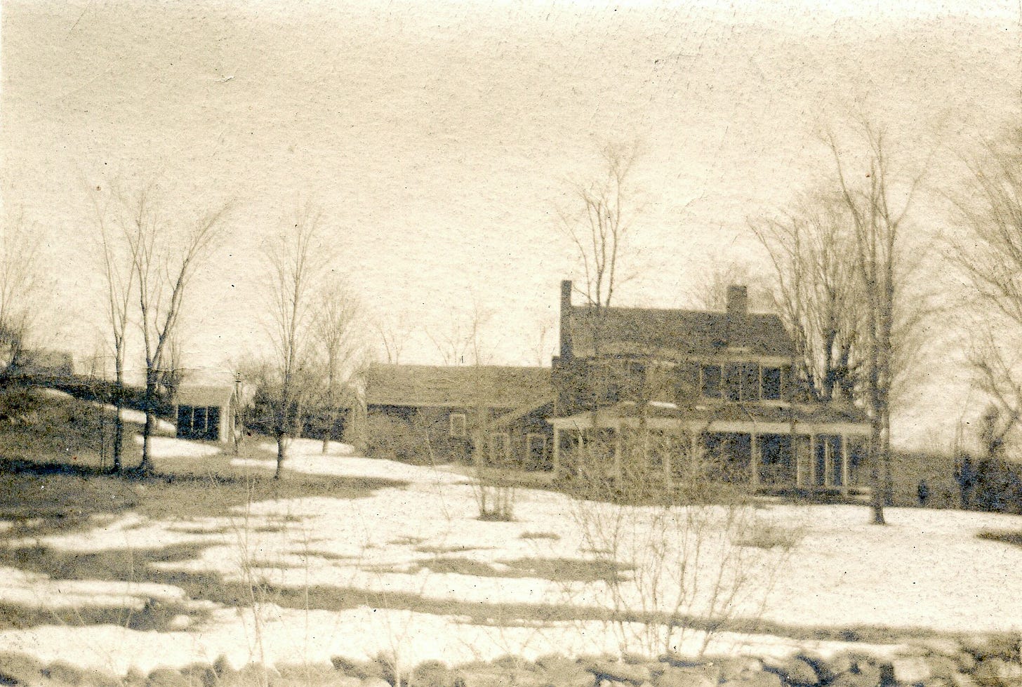 House with wrap around porch in a snowy yard.