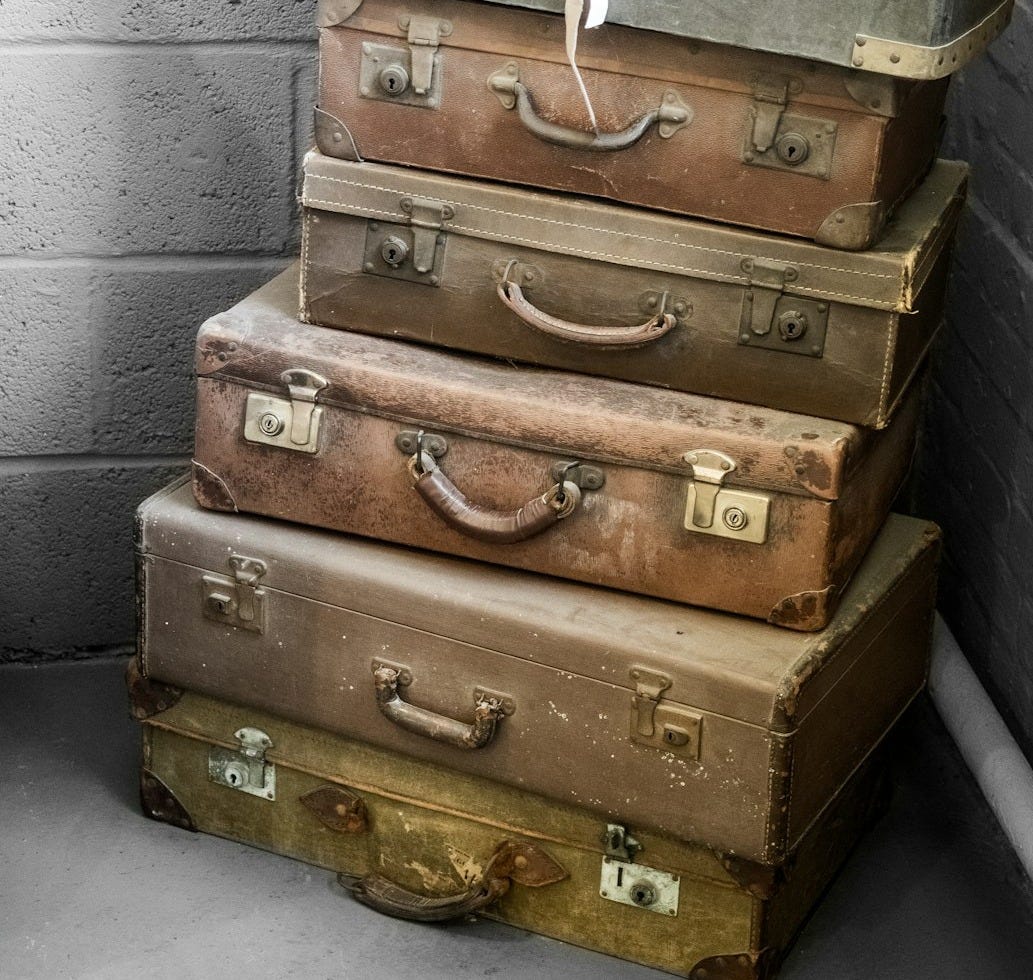 a stack of suitcases sitting next to a brick wall