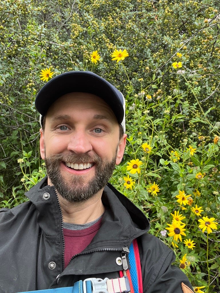 A person smiling in front of yellow flowers

Description automatically generated with medium confidence