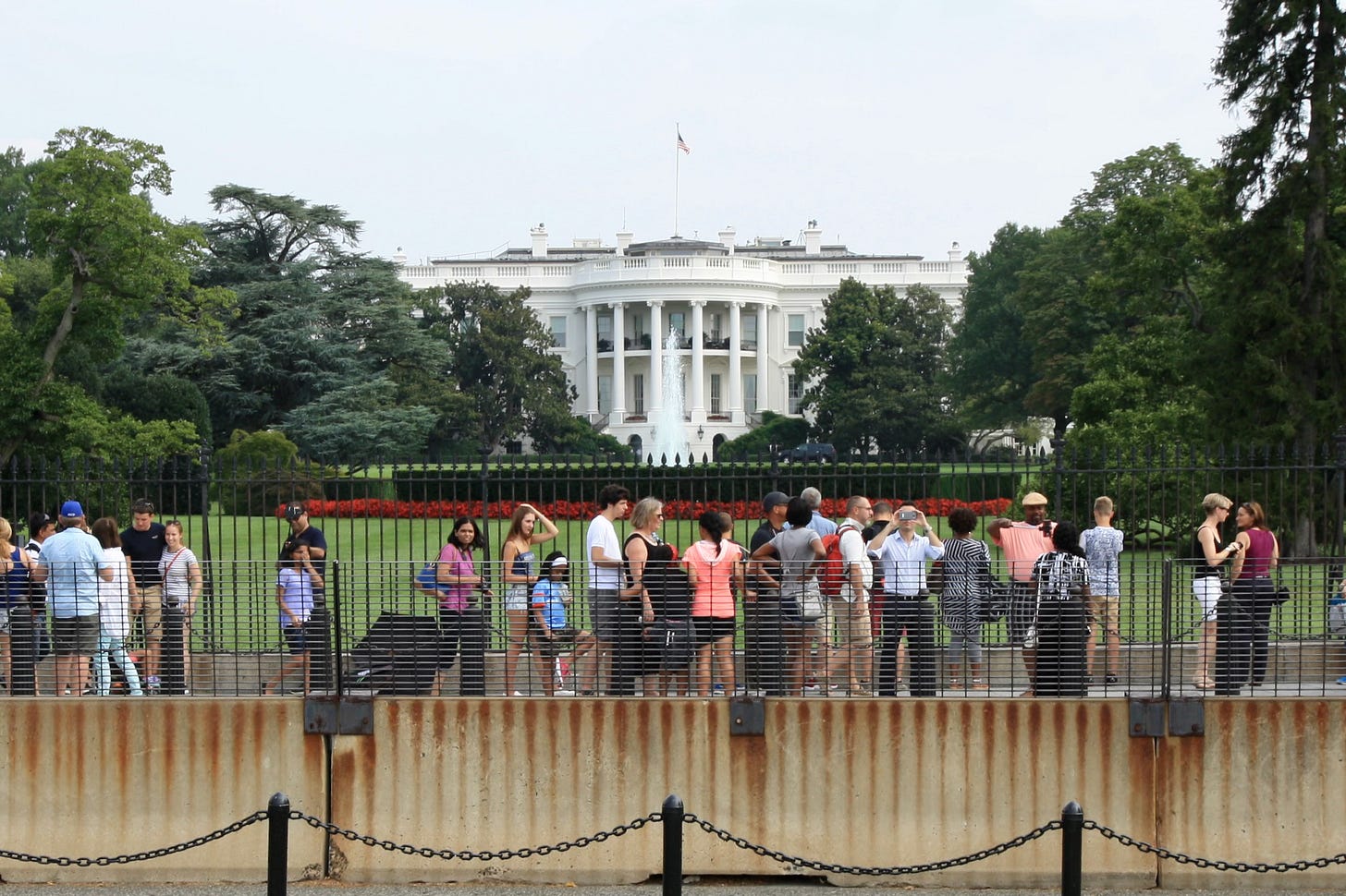 The White House with onlookers outside a cast-iron fence