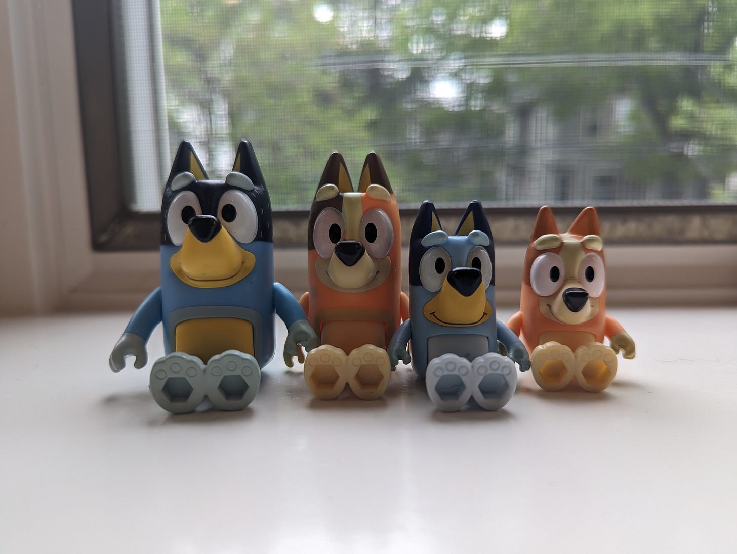 Figurines of four Bluey characters in front of a window