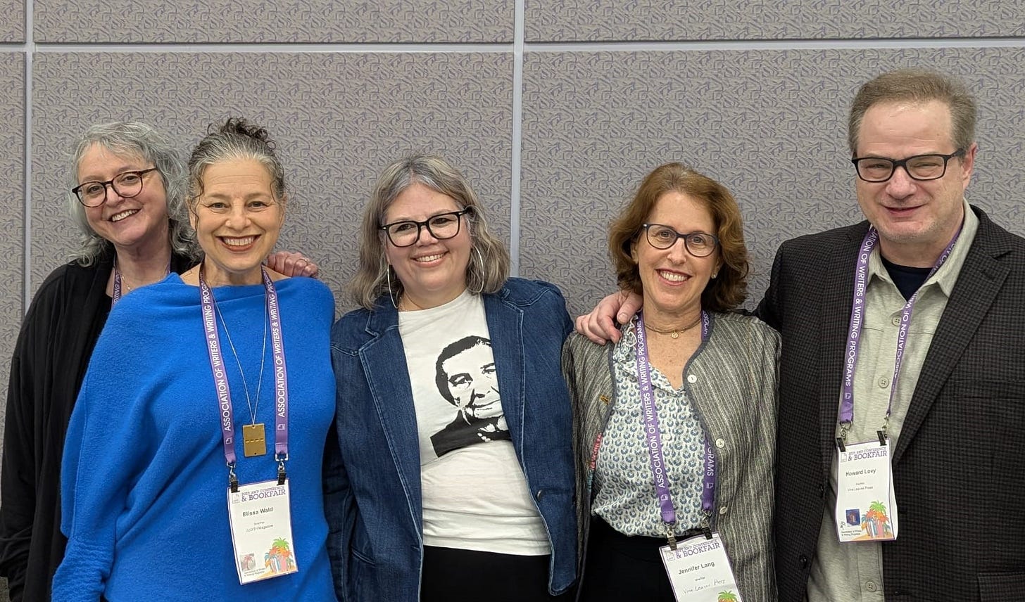 Five white people lined up against a conference room wall.