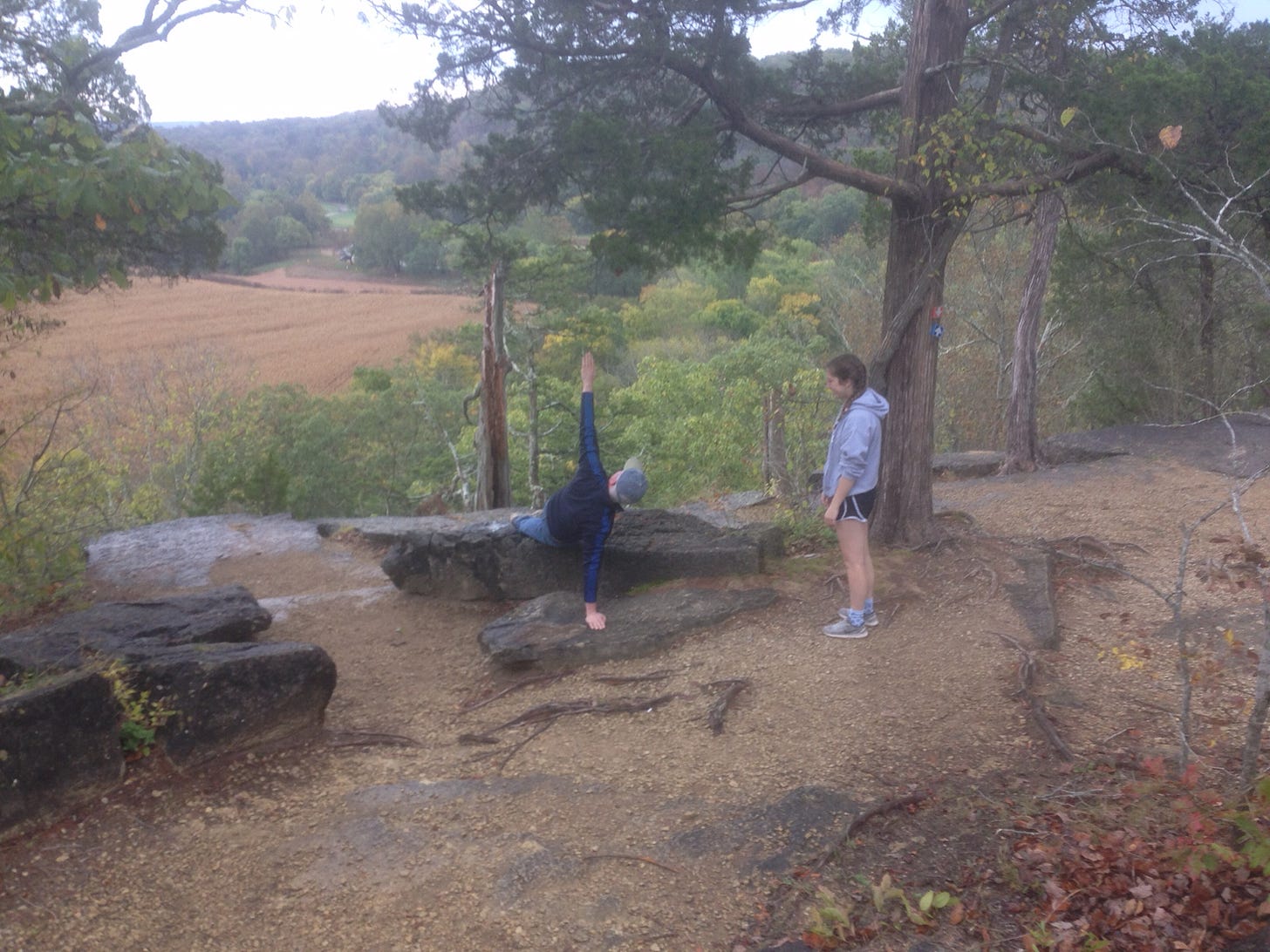 My dad planking on a rock on a bluff over a river valley, my sister looking on 