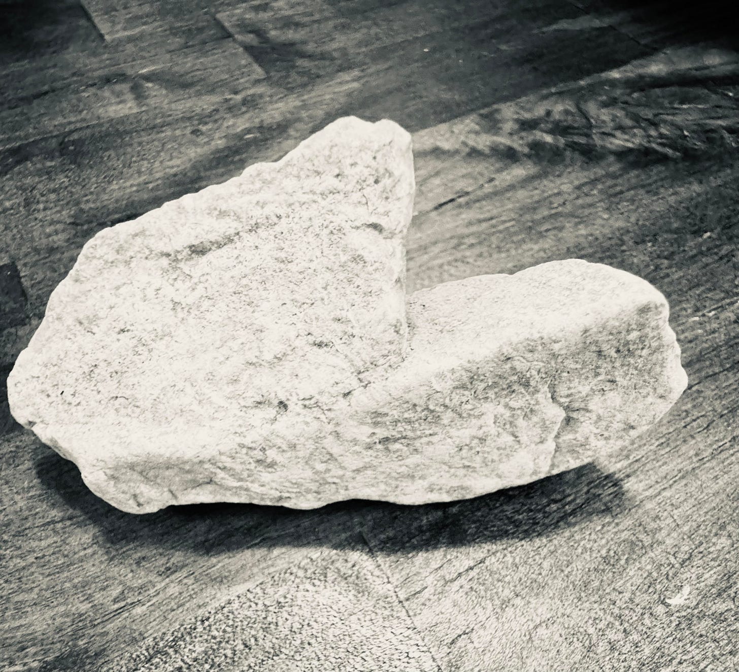 Scene: Black and white image of a heart shaped rock on a butcher block counter.
