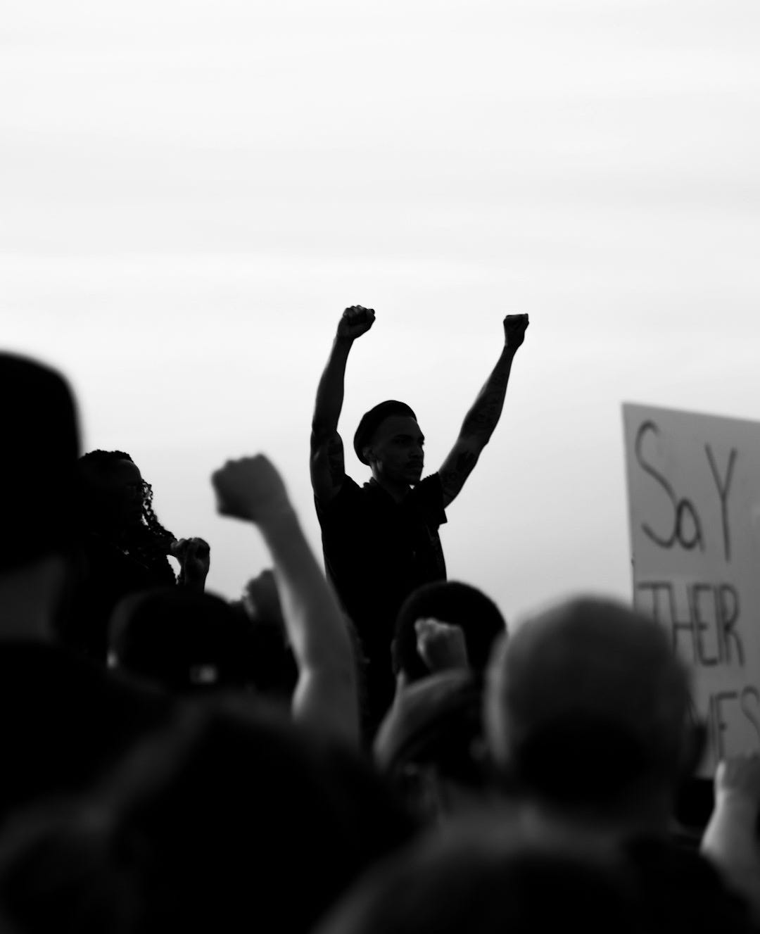 grayscale photo of people raising their hands
