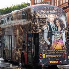 A double decker bus with a Hunger Games TBOSAS poster all over it.