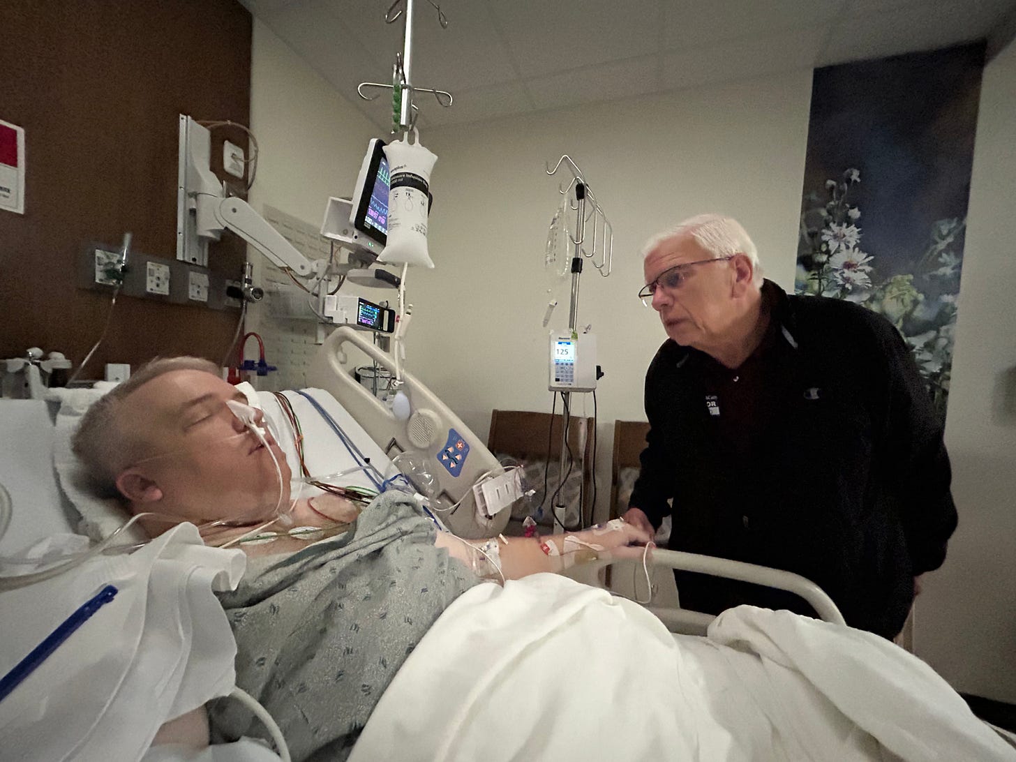 Adam recovering in a hospital bed following liver surgery, connected to medical monitors and an NG tube while resting in the immediate postoperative period.