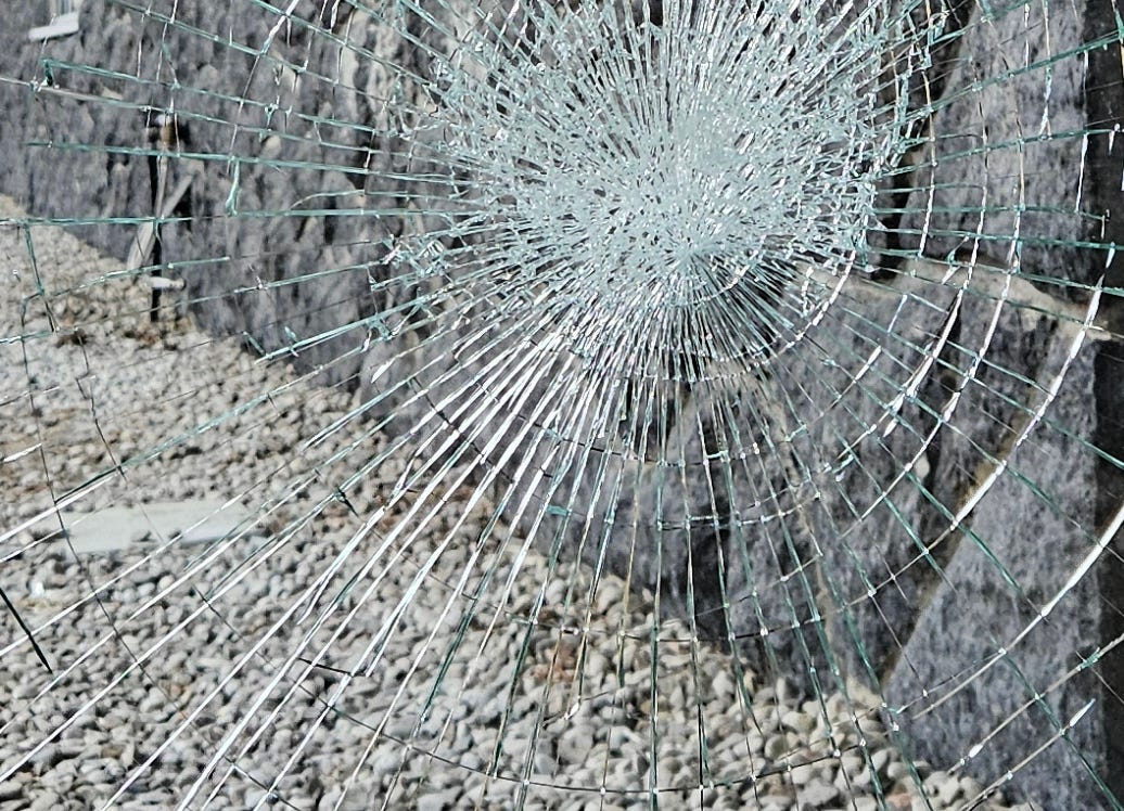 A stone wall and pebbled ground behind a cracked window