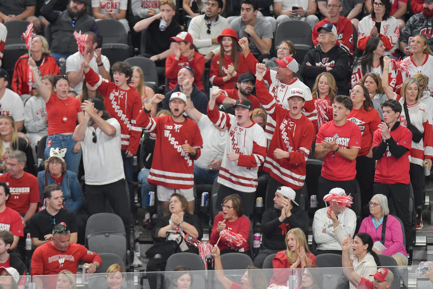 A group of Wisconsin hockey fans cheering from the stands A group of Wisconsin hockey fans cheering from the stands