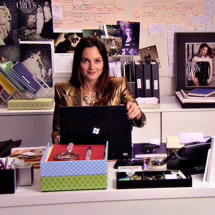 This may contain: a woman sitting at a desk with a laptop in front of her, surrounded by office supplies