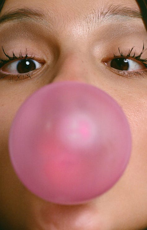 1: A pair of over the ear, wired headphones atop a blue sky with a cloud. The bottom text reads in an all-caps: “Choose your escape route.” 2: A close up of Olivia Rodrigo’s face, only her eyes and eyebrows are visible. She’s blowing bubblegum. The large, pink circular bubble obscures the singer’s nose and mouth. Her eyes focused the pubble at the center of the image. 3: Repeated black and white photograph of a couple kissing. 4: Black text in a techno-esque font on a white background reads “outside the party inside the dream.” 5: Photograph of a tarp printed with an image of a blue sky with white clouds. Two slits at the bottom of the tarp allow three children to peek through the tarp. 6: Screenshot of the comment section of a Tik Tok video. Green trees are visible in the top of the image, above the open comment section. The comment section is a white box that takes up the majority of the image. Tik Tok user danica comments “what aesthetic is this ? x.” Tik Tok user marinersarchive responds “walking outside.” The original commenter, danica, responds “Thank you!” 7: Illustration of a person with dark hair sitting face down in a bathtub surrounded by photographs of men who look like pop idols. A can with cigarette butts and a smartphone sit on the edge of the bathtub. 8: A young teenager sitting on a bike looks over her shoulder directly at the camera. She is wearing a flower crown, a costume elf ear, and her face is painted with a pink flower. 9: A soft photograph of daisies blurred, as if in motion, against a light blue background.