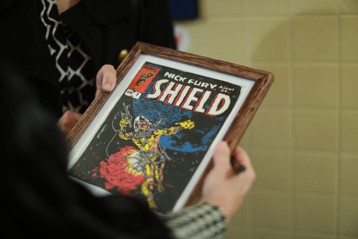 Duke Stableford (left, in his classroom at Chancellor High School in 2002) created 30 needlepoint interpretations of Marvel comic book covers (right, photo credit Karen Pearlman). They will be on display at UMW this evening before author Bob Batchelor's Great Lives lecture on Marvel Comics creator Stan Lee. Photos courtesy UMW.
