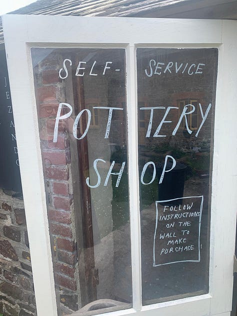L-R: pink flowers, Emily (a white woman wearing glasses) wears a raincoat, hood up, taking a selfie in front of wildflowers, a door with "self-service pottery shop" written on it