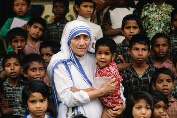 Mother Teresa accompanied by children at her mission in Calcutta, India.