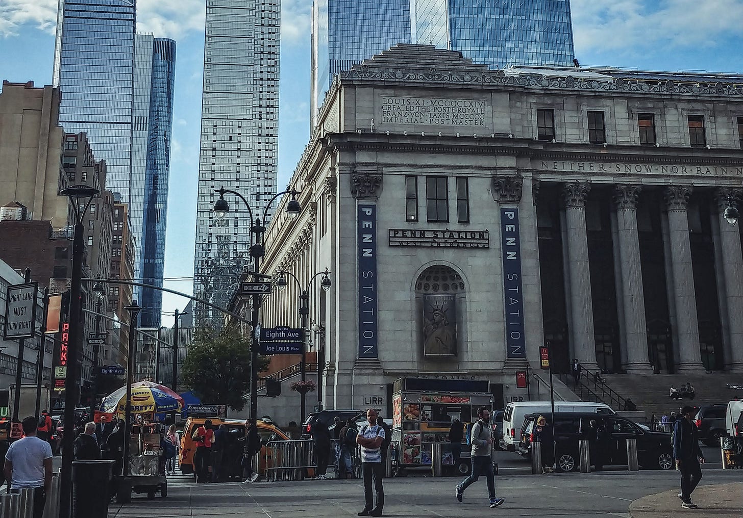 A bustling scene of Penn Station with Hudson Yards skyscrapers in the background in New York City.