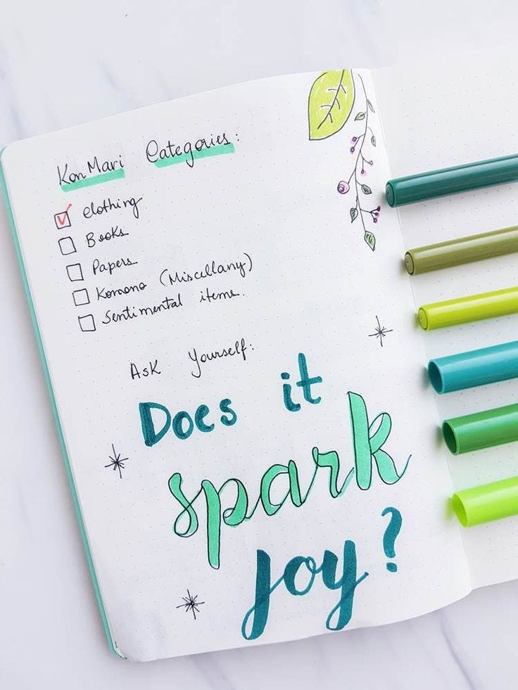 This may contain: an open notebook with writing on it next to markers and pencils that read does it spark joy?