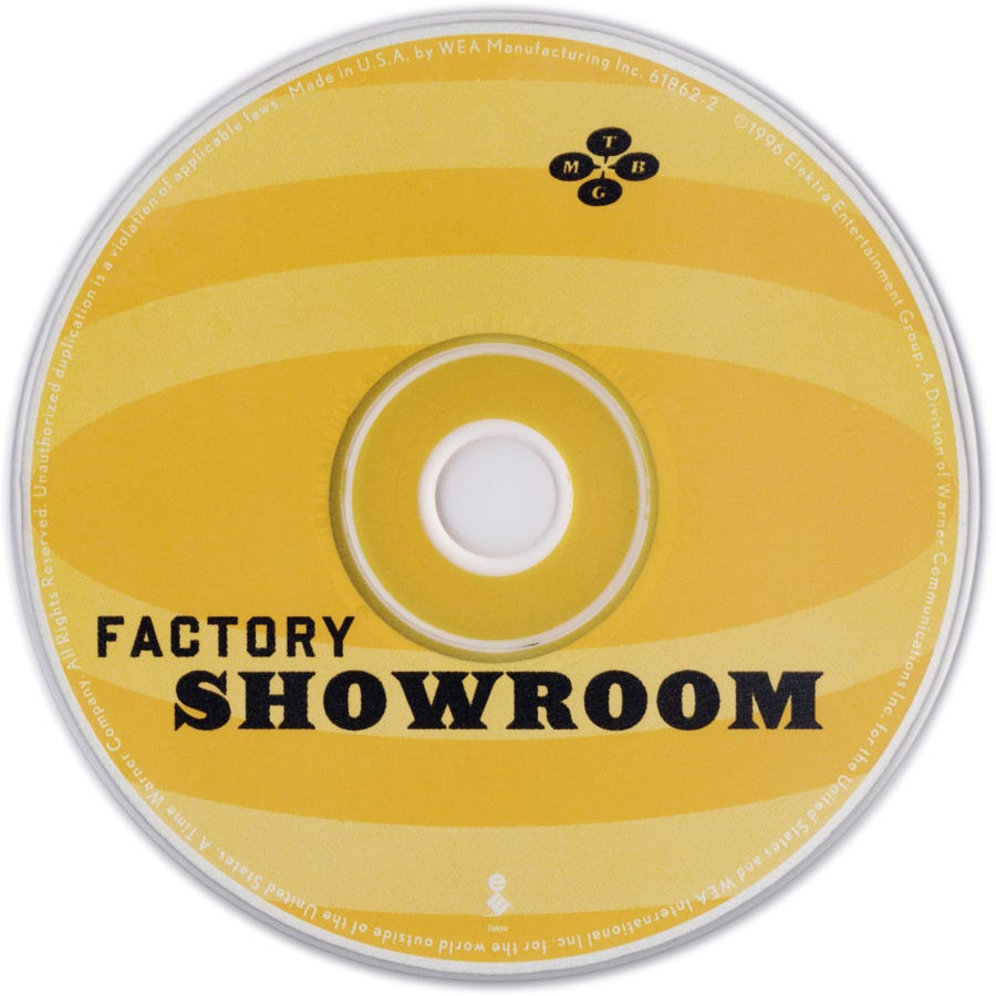 Yellow and gold compact disc for They Might Be Giants’ album Factory Showroom, with abstract concentric shapes and the album title in black. Yellow and gold compact disc for They Might Be Giants’ album Factory Showroom, with abstract concentric shapes and the album title in black.