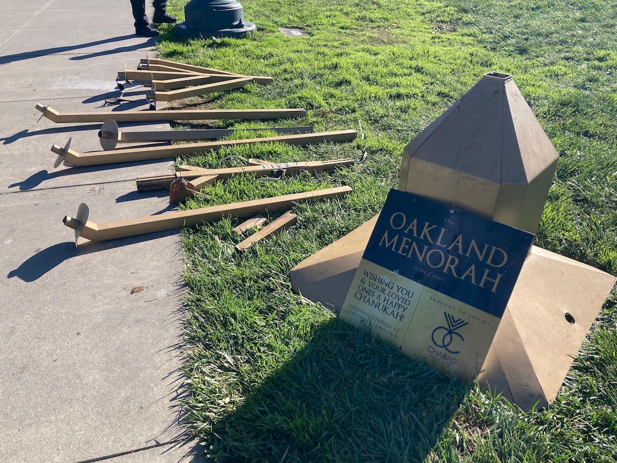 Parts of a large golden menorah on the grass.
