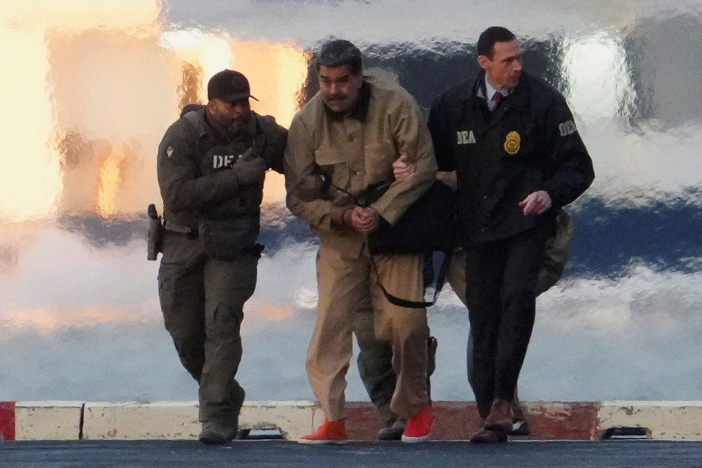 Venezuelan President Nicolas Maduro in handcuffs, escorted by two DEA agents.
