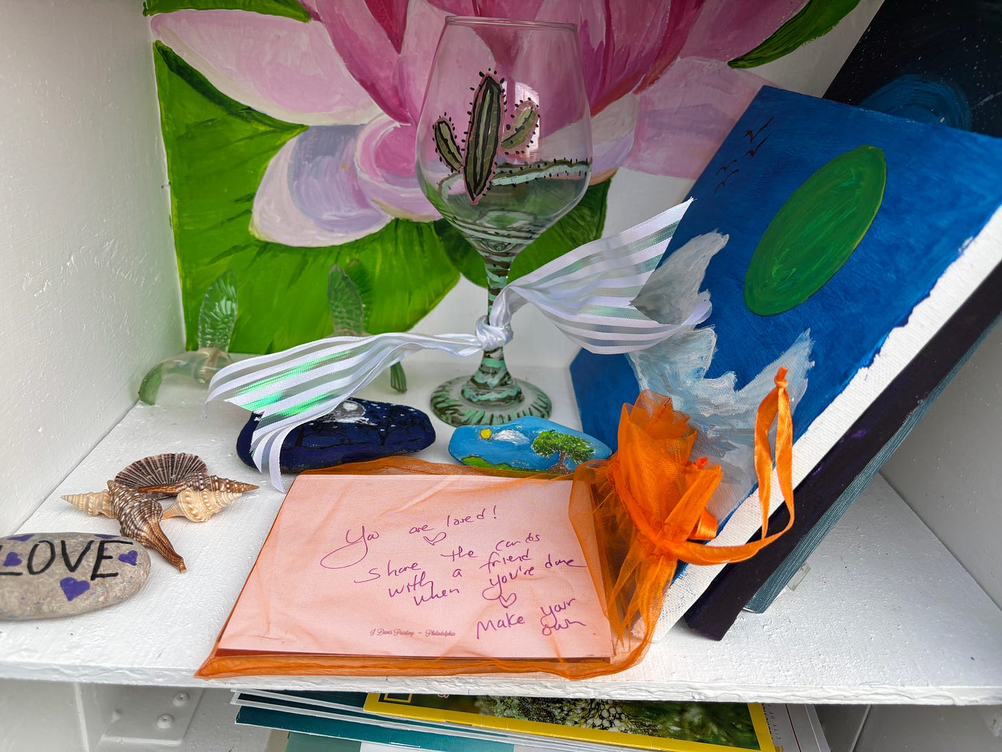 a shelf with small paintings, cards and painted rocks