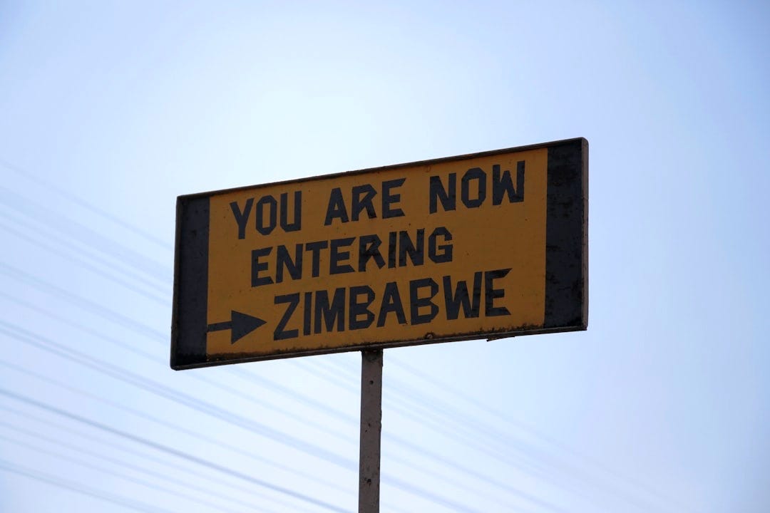 a street sign that says you are now entering zimbawe a street sign that says you are now entering zimbawe