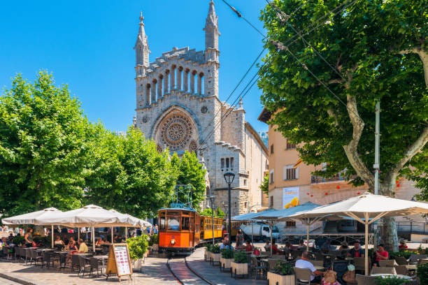 Historic Tram driving in Street of Soller Mallorca Spain Soller, Spain - June 8, 2016: Historic Tram of the Soller Tramway line driving in a street in Soller, Mallorca, Spain. The tramway line is active since 1913 and connects the towns of Soller and Port de Soller, a distance of 4,8 kilometers. soller train stock pictures, royalty-free photos & images