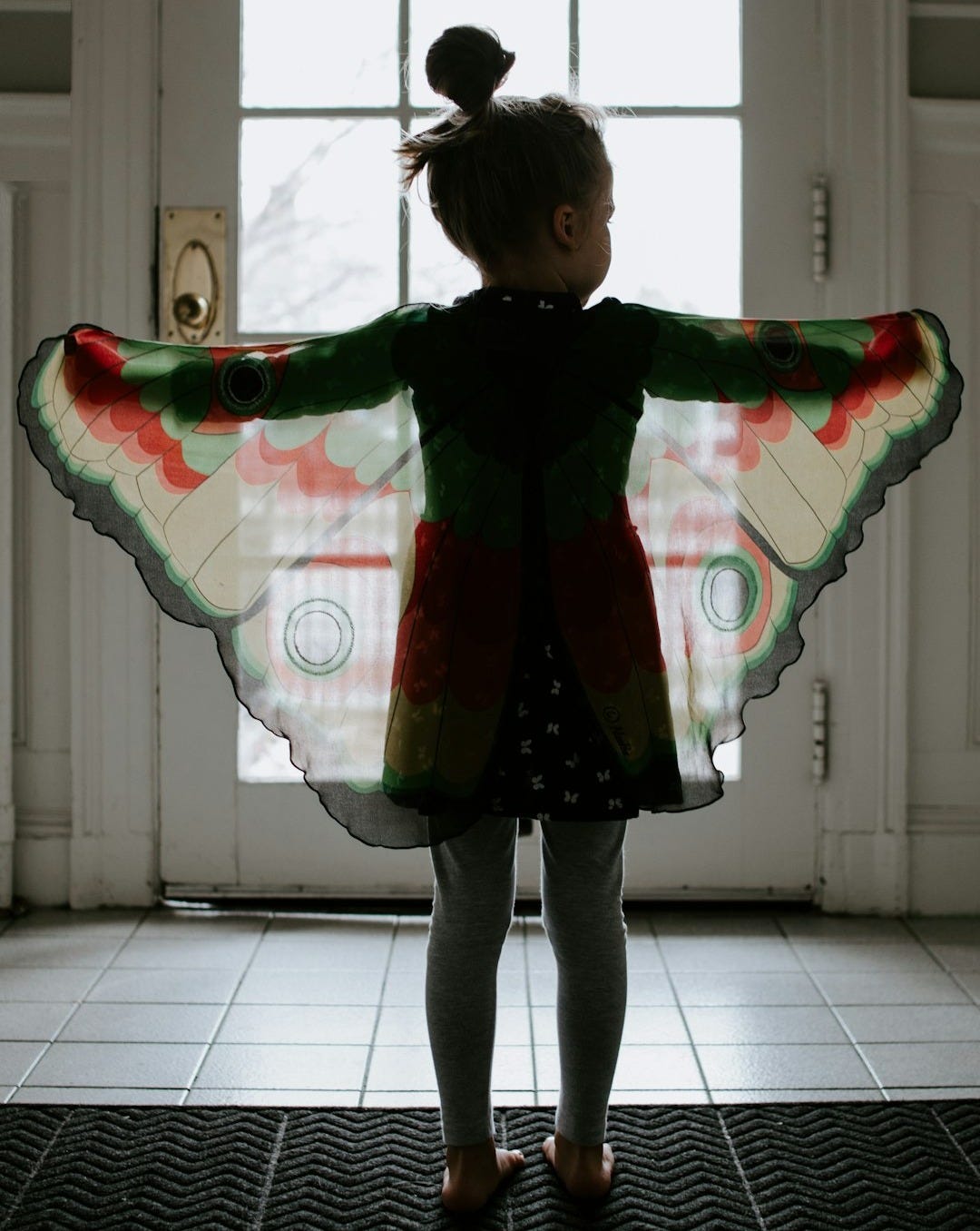girl in black and red plaid jacket standing on white floor tiles