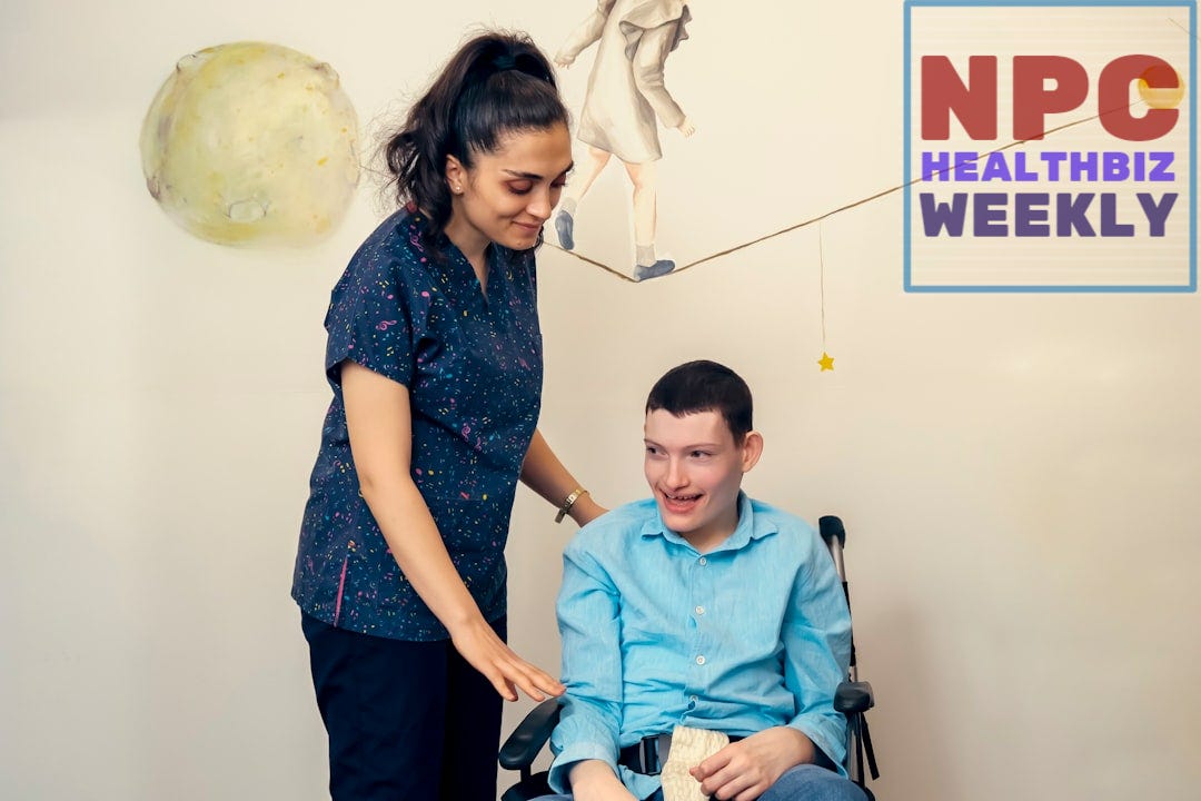 a woman standing next to a man in a wheel chair