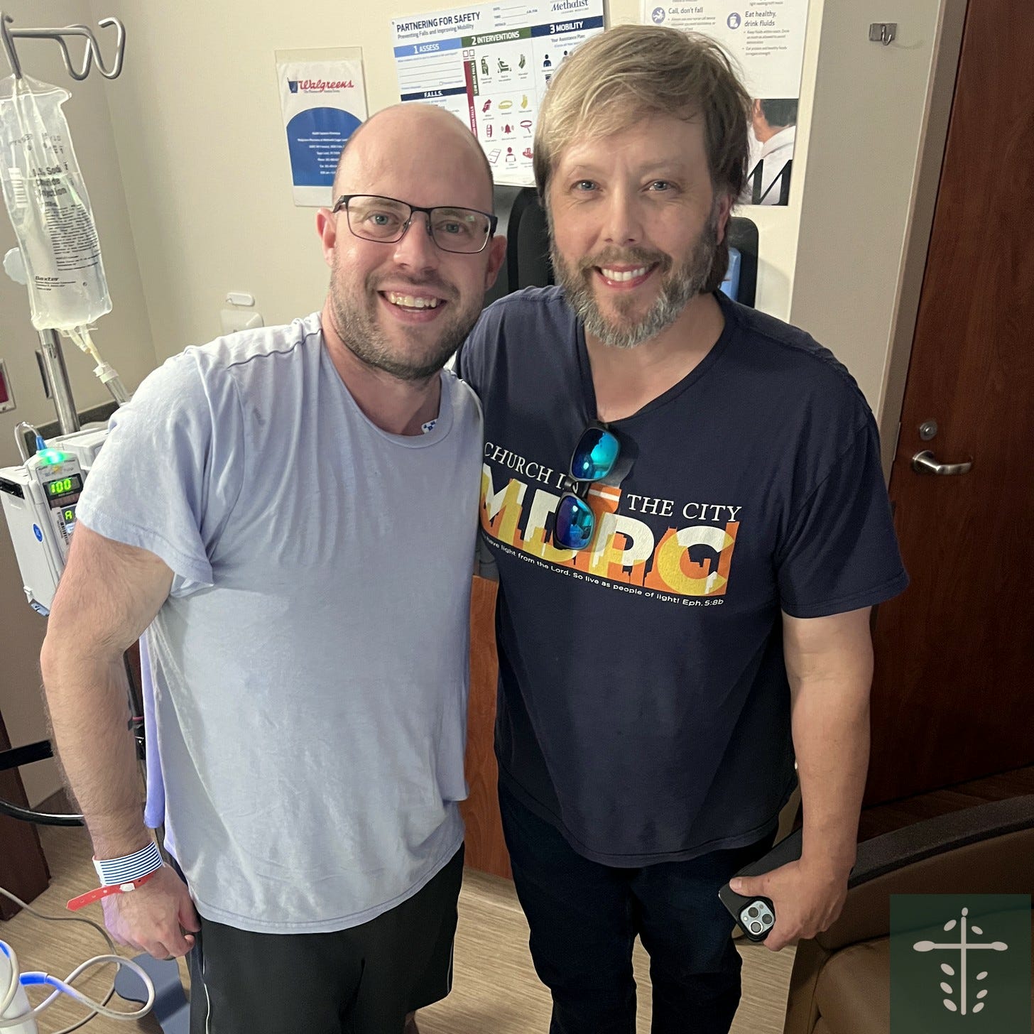 Mike, standing beside an IV pole in his hospital room, smiling next to his friend Michael. Mike, standing beside an IV pole in his hospital room, smiling next to his friend Michael.