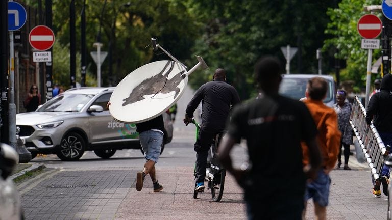 People remove a new artwork by Banksy, depicting a howling wolf painted on a satellite dish that was placed on a shop roof in Peckham, south London. The artist's latest artwork comes a day after he unveiled three monkeys painted on a bridge in Brick Lane, east London. Picture date: Thursday August 8, 2024.

