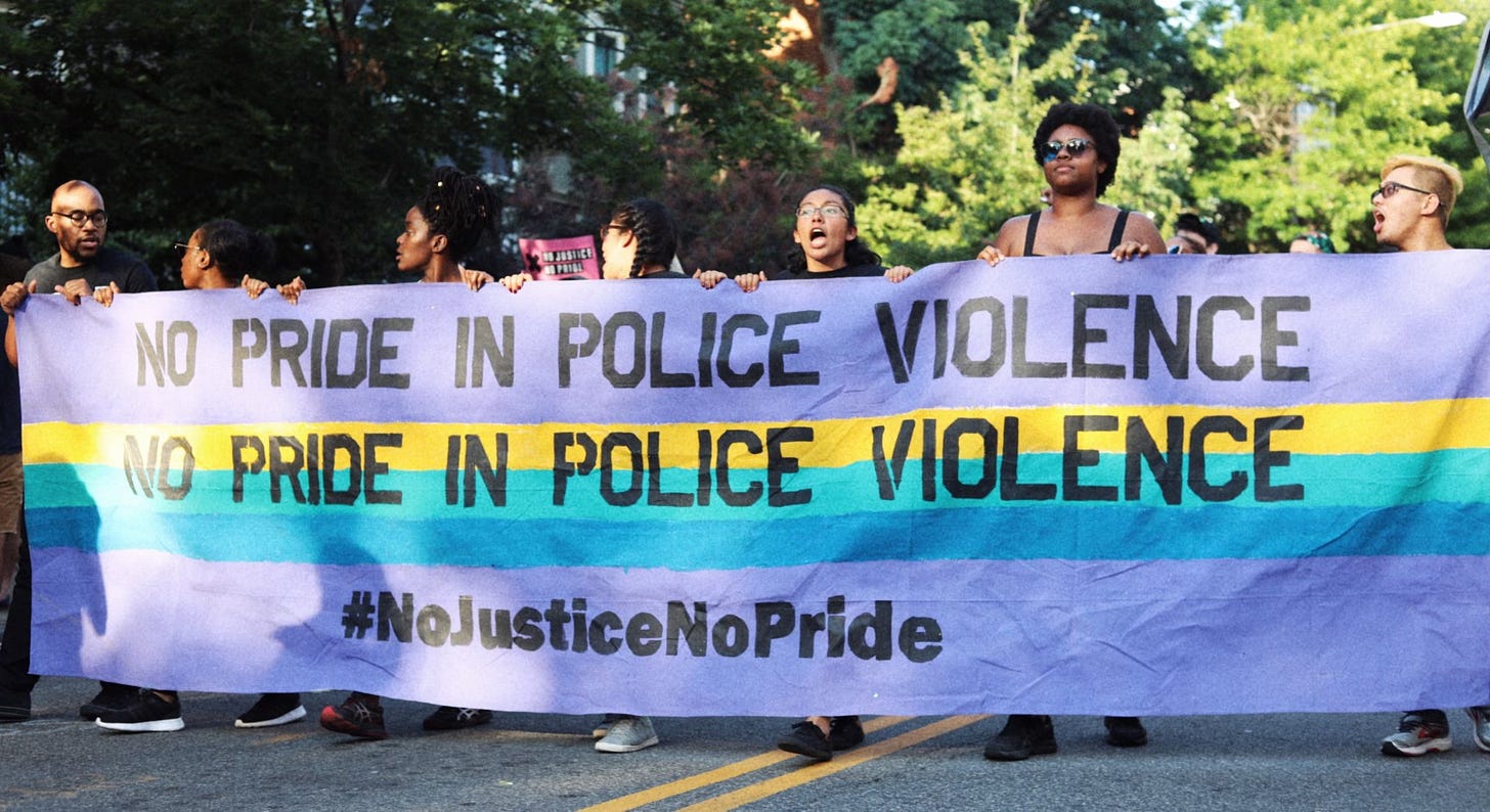 Protestors at past DC Pride holding a sign saying "No Pride in Police Violence" and "#NoJusticeNoPride"