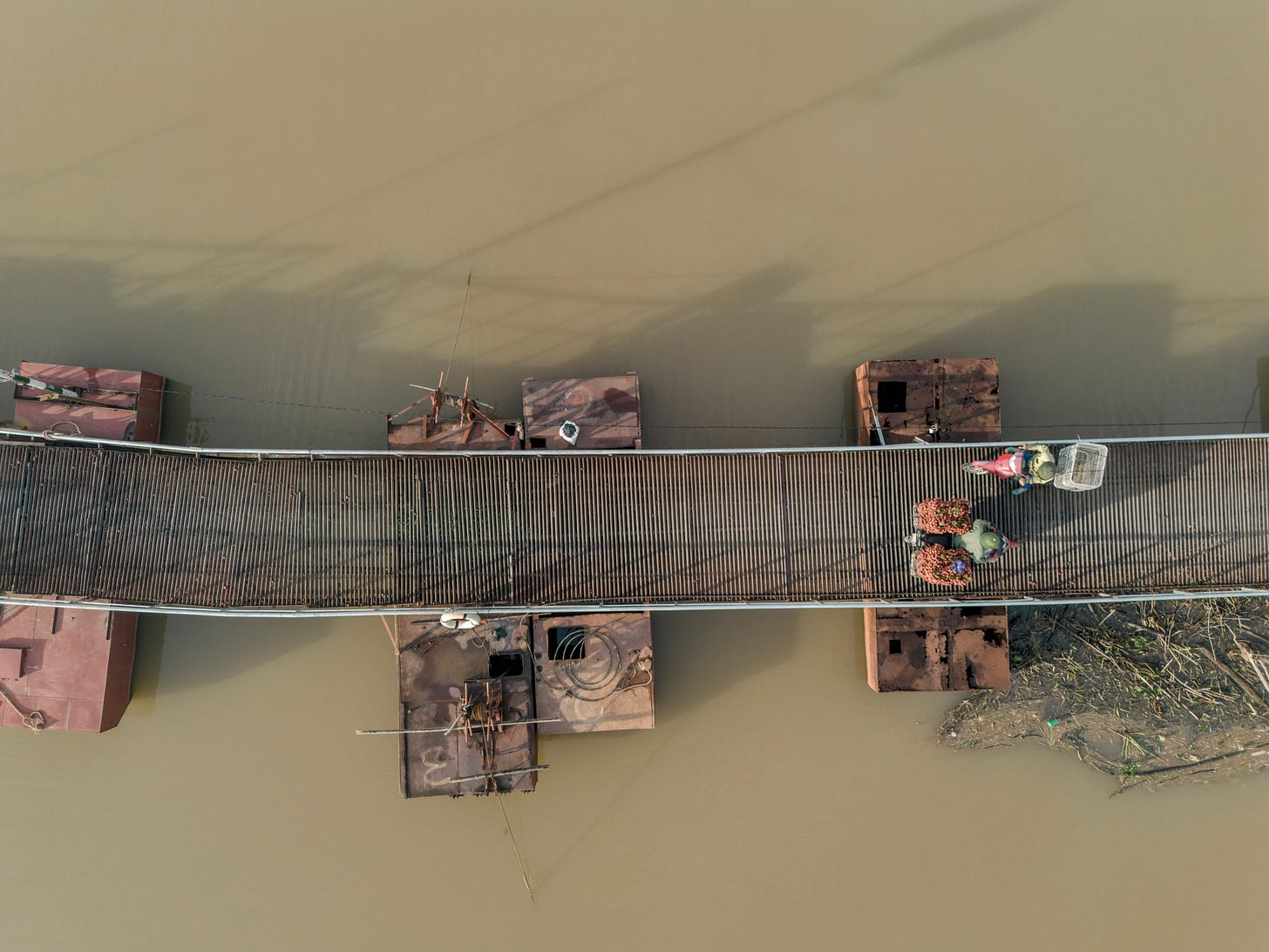Aerial view of a bridge in Bac Giang, Vietnam with people carrying lychees across it.